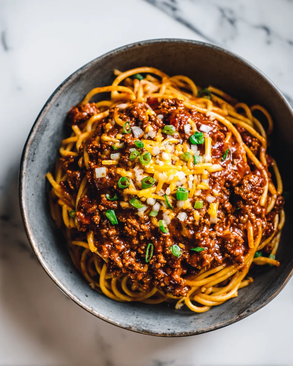Delicious Cincinnati Chili served over spaghetti with cheese and onions, perfect for cozy gatherings and holiday meals.