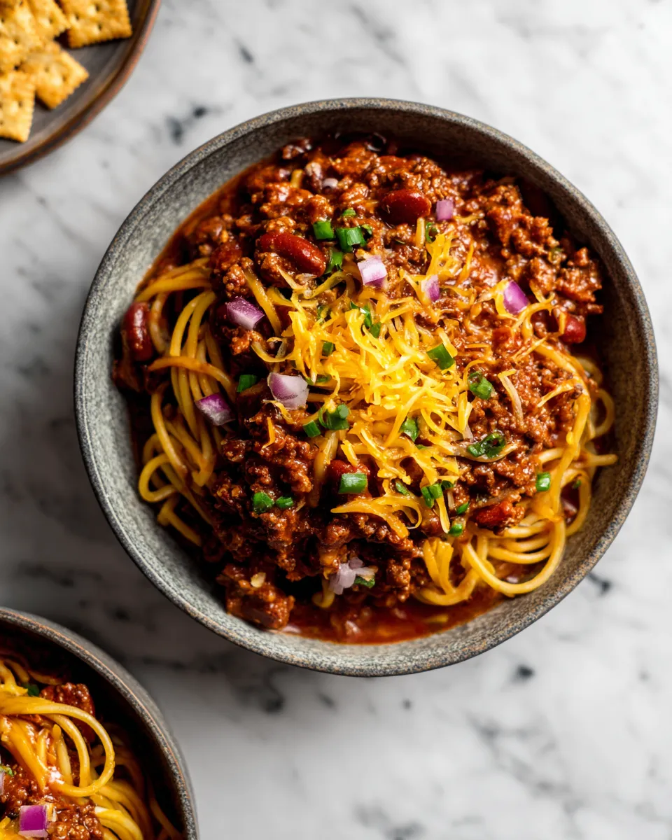 Delicious Cincinnati Chili served over spaghetti with cheese and onions, perfect for cozy gatherings and holiday meals.