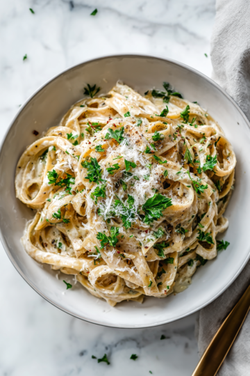 A delicious bowl of skinny fettuccini garlic Alfredo topped with fresh parsley, served as a guilt-free pasta dish